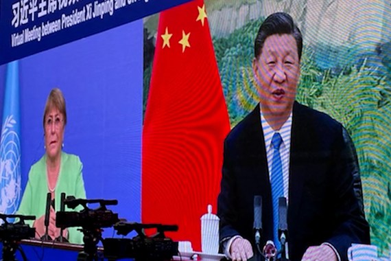 United Nations High Commissioner for Human Rights (OHCHR) shows a screen of UN human rights chief Michelle Bachelet (L) attending a virtual meeting with China's President Xi Jinping