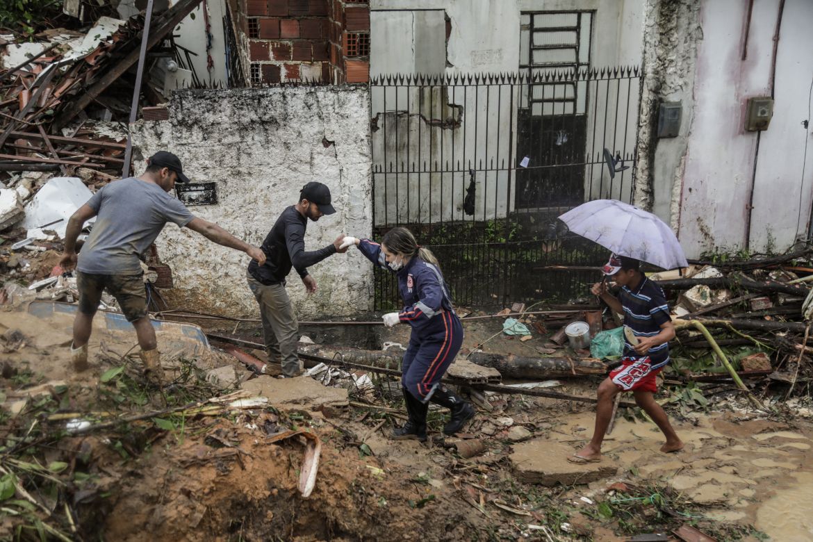 This handout picture release by the Recife City Hall shows residents and rescue workers walking amid the debris of a landslide that destroyed several houses in the community Jardim Monte Verde, Ibura neighbourhood, in Recife, Pernambuco State, Brazil, on May 28, 2022. - Torrential rains that have plagued Brazil's northeastern Pernambuco state since Tuesday have left at least 34 dead, 29 of which occurred over the last 24 hours, according to the latest official update. (Photo by Diego NIGRO / RECIFE CITY HALL / AFP) / RESTRICTED TO EDITORIAL USE - MANDATORY CREDIT "AFP PHOTO / RACIFE CITY HALL / DIEGO NIGRO" - NO MARKETING - NO ADVERTISING CAMPAIGNS - DISTRIBUTED AS A SERVICE TO CLIENTS