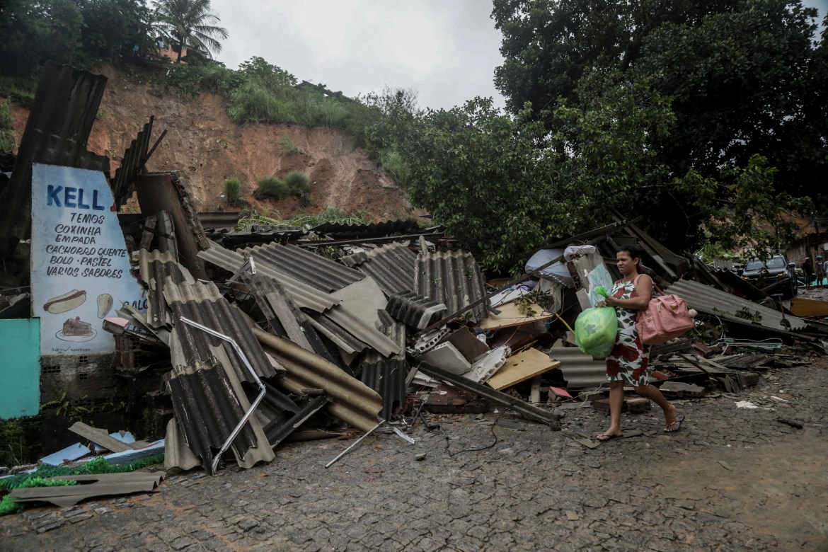 This handout picture release by the Recife City Hall shows a woman passing by a house destroyed by a landslide in the community Jardim Monte Verde, Ibura neighbourhood, in Recife, Pernambuco State, Brazil, on May 28, 2022. - Torrential rains that have plagued Brazil's northeastern Pernambuco state since Tuesday have left at least 34 dead, 29 of which occurred over the last 24 hours, according to the latest official update. (Photo by Diego NIGRO / RECIFE CITY HALL / AFP) / RESTRICTED TO EDITORIAL USE - MANDATORY CREDIT "AFP PHOTO / RACIFE CITY HALL / DIEGO NIGRO" - NO MARKETING - NO ADVERTISING CAMPAIGNS - DISTRIBUTED AS A SERVICE TO CLIENTS