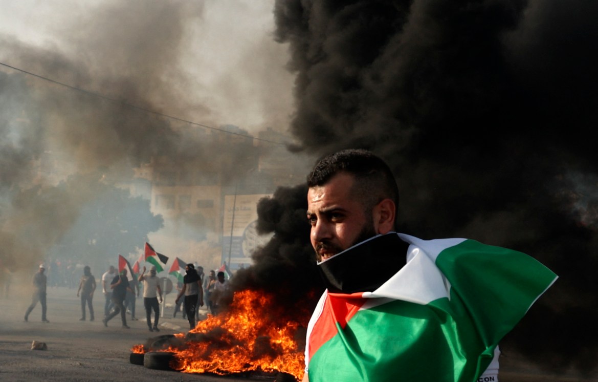 A protester draped in a Palestinian flag demonstrates to denounce the annual "flag march" through the occupied East Jerusalem