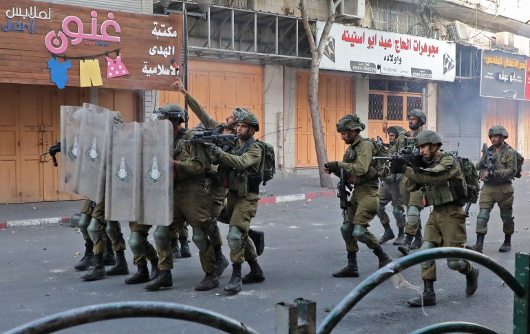 Israeli army soldiers approach Palestinian protesters with riot shields during clashes following a demonstration to denounce the annual nationalist 'flag march' through Jerusalem, in the city of Hebron in the occupied West Bank