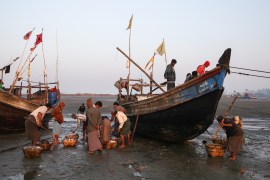 Rohingya fishermen gather around boats on the shore