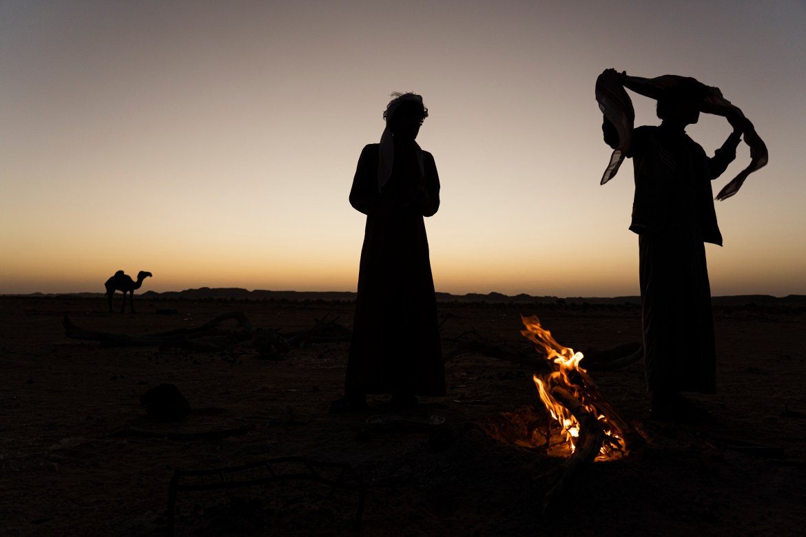 Bedouin men stand around a campfire between Rumah and the "Empty Quarter"