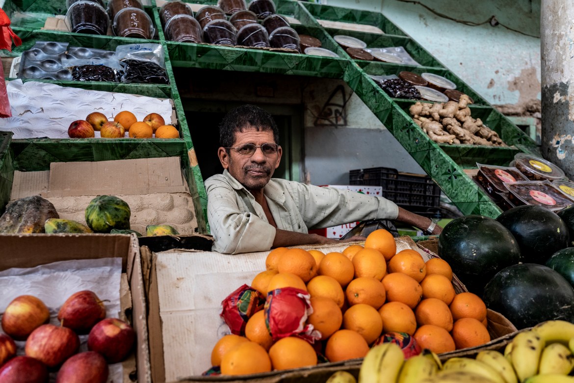 A man sits in the middle of his fruit and vegetable stall at a food market in Seiyun.