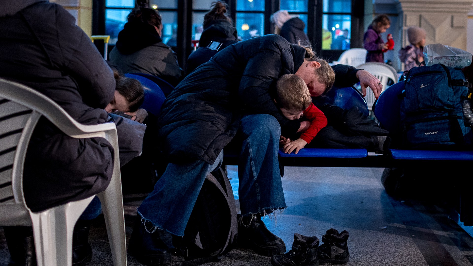 A woman and child sleep in a train station