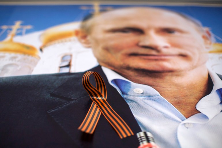 A fita laranja de São Jorge, um símbolo amplamente associado aos rebeldes pró-Rússia na Ucrânia, é colocada em um pôster representando o presidente da Rússia, Vladimir Putin