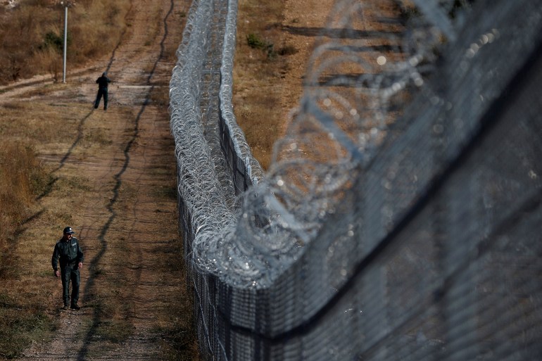 A Bulgarian border policeman walks near the barbed wire fence constructed on the Bulgarian-Turkish border, near Lesovo, Bulgaria