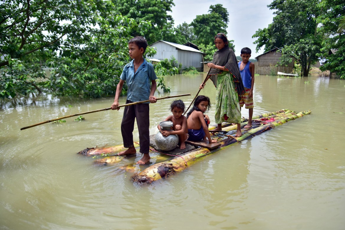 Villagers row a makeshift raft through a flooded field to reach a safer place at the flood-affected Mayong village in Morigaon district