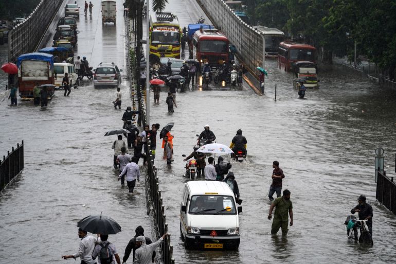 People wade through a waterlogged road after heavy rains in Mumbai, India