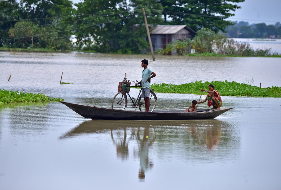 People move in a boat through a flooded field in Morigaon district in the northeastern state of Assam