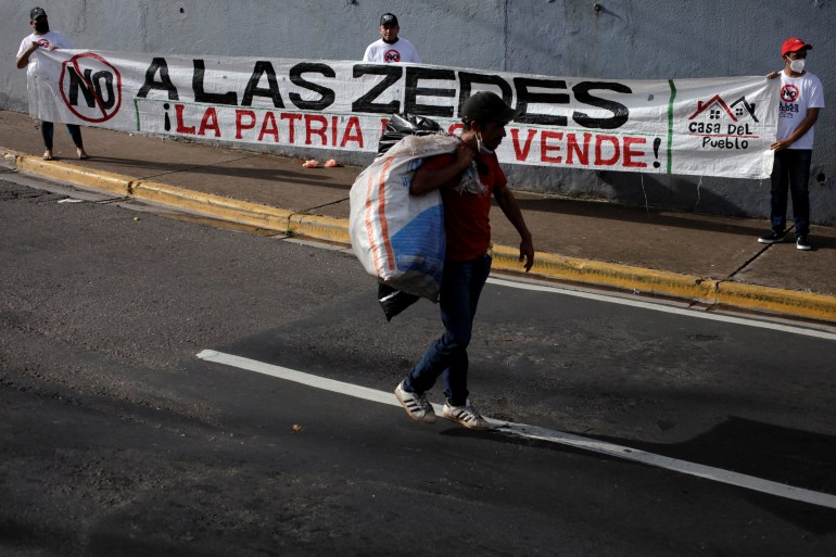     A man walks past protesters rallying against ZEDE in Honduras