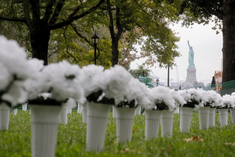 The Statue of Liberty is seen behind rows of potted flowers symbolising victims of gun violence