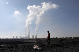 A child collecting chunks of coal looks on at a colliery while smoke rises from the Duvha coal-based power station owned by state power utility Eskom, in Emalahleni, in Mpumalanga province, South Africa, June 2, 2021 [File: Siphiwe Sibeko/Reuters]