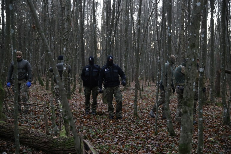 Polish law enforcement officers approach a group of migrants in a forest near the Polish-Belarusian border outside Narewka, Poland November 9, 2021. The group of migrants was later guided out of the forest by Polish border guards and taken to a detention centre. 