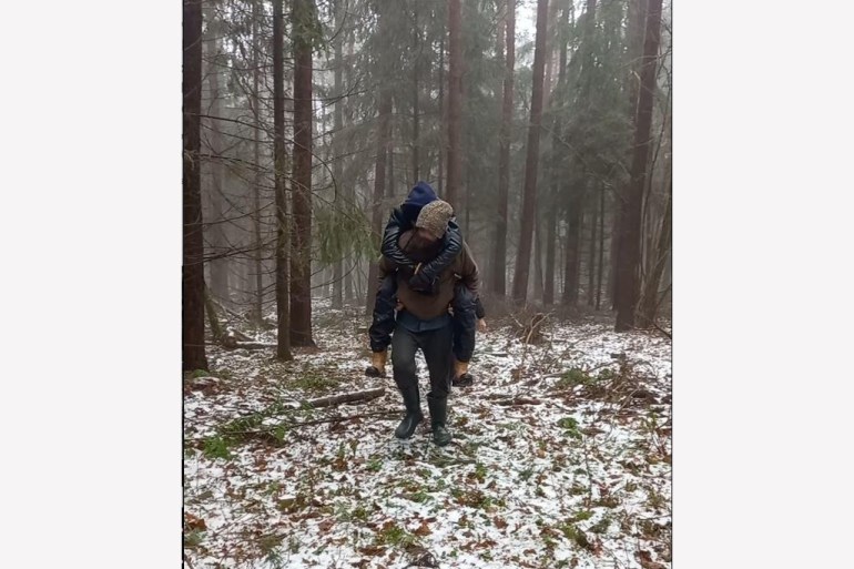A photo of a person carrying another person through the snowy forest.