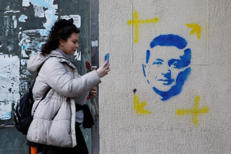 A woman walks in front of graffiti depicting Ukrainian President Volodymyr Zelenskyy, in Podgorica, Montenegro