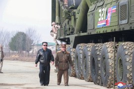 Kim Jong Un walking past a Hawsong-17 missile on a tarmac.
