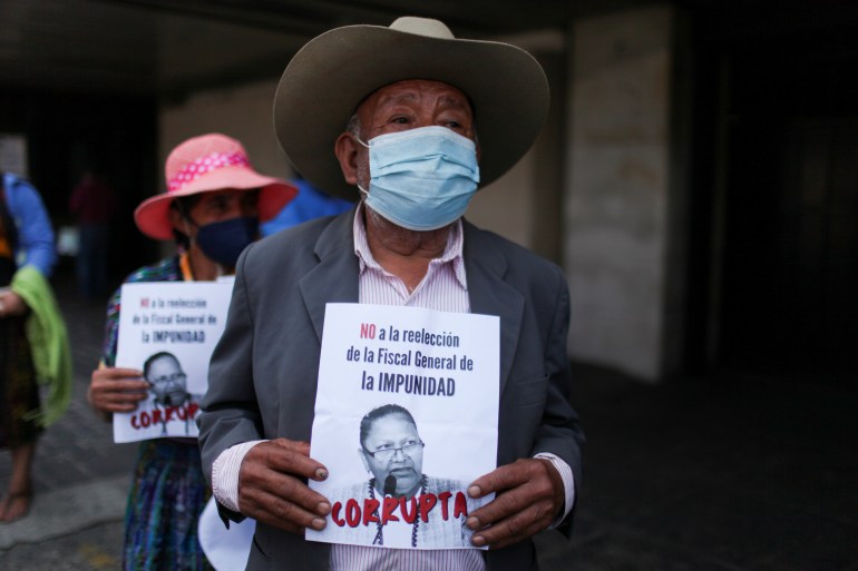 Protesters hold signs denouncing Guatemala's attorney general