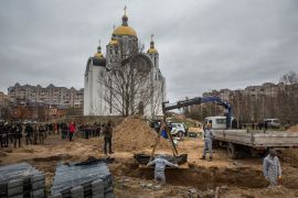 Bodies are seen being exhumed by forensic technicians in Bucha, Ukraine