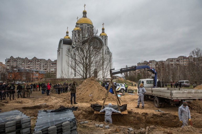 Bodies are seen being exhumed by forensic technicians in Bucha, Ukraine