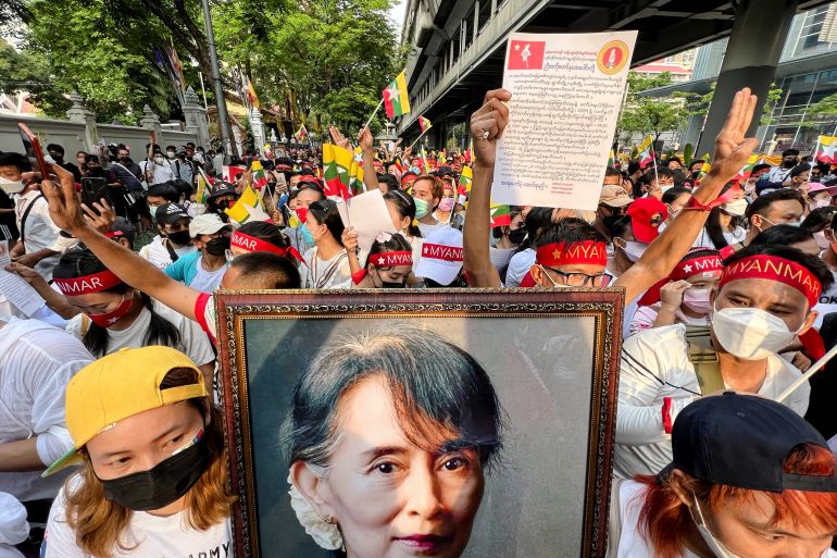 Myanmar migrant workers demonstrate against the military coup carrying pictures of Aung San Suu Kyi and wearing red bandanas as they march in Bangkok