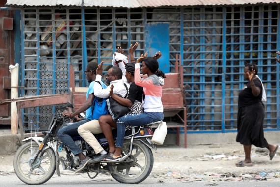 Residents raise their arms on a motorbike as they flee their homes in Port-au-Prince