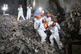 Rescue workers are seen carrying a survivor at the site of the building's collapse in Changsha