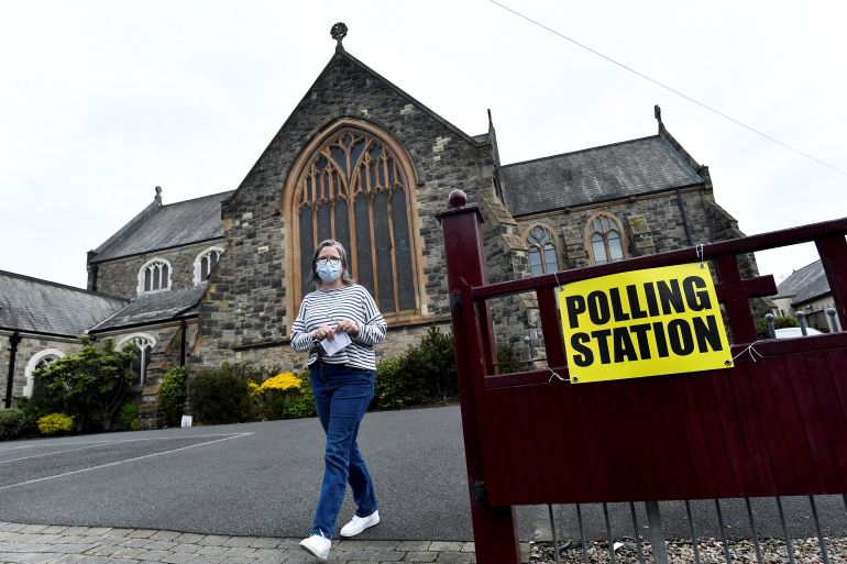 A woman walks outside a polling station in St Peter's Church of Ireland on the day of the Northern Ireland Assembly elections in Belfast