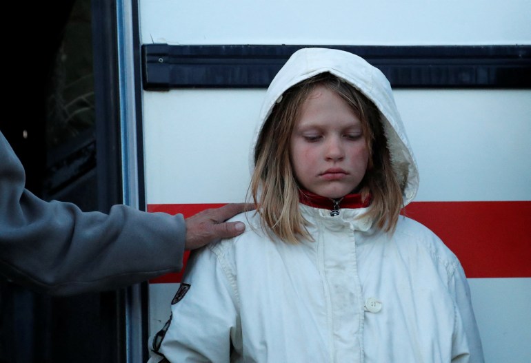 A girl, who was evacuated from Mariupol in the course of Ukraine-Russia conflict, stands outside a bus near a temporary accommodation center in the village of Bezimenne in the Donetsk region, 