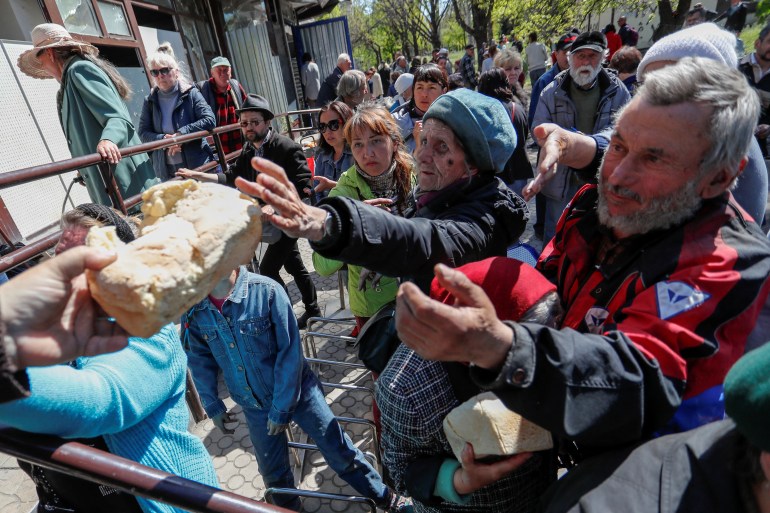 People receive bread during the distribution of humanitarian aid in the course of Ukraine-Russia conflict in the southern port city of Mariupol, Ukraine