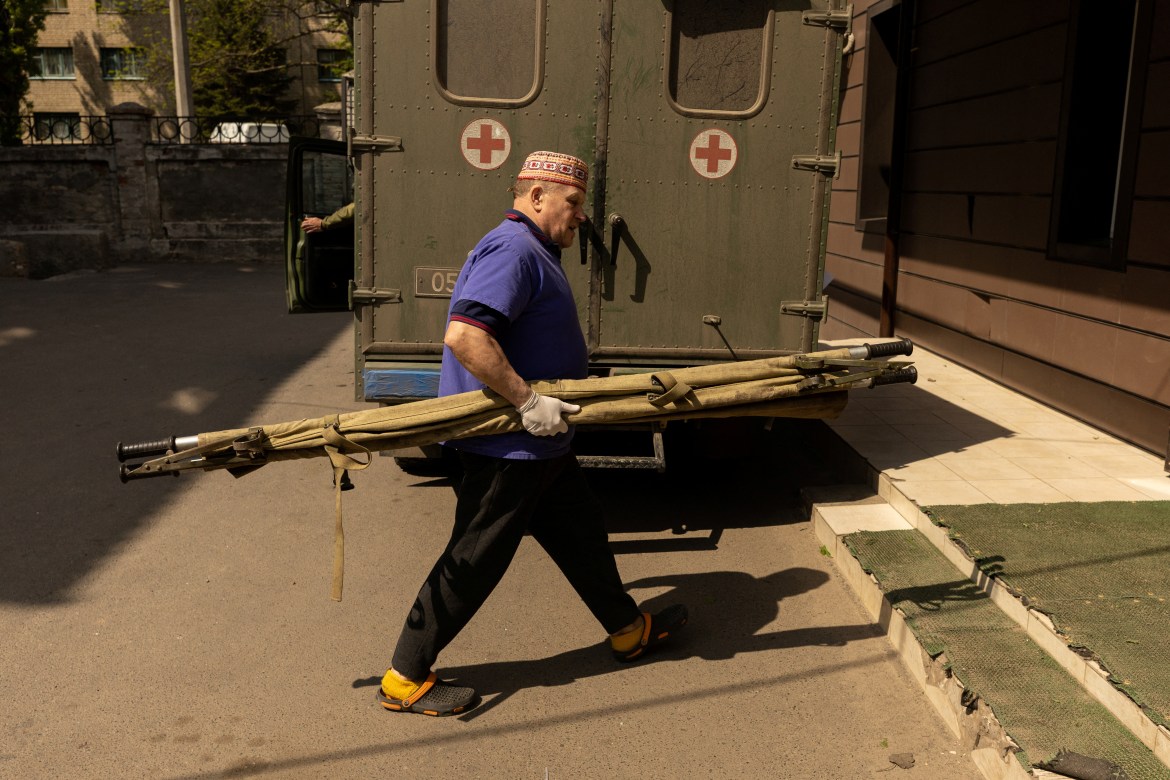 A nurse carries a stretcher past an ambulance which is carrying the body of a dead Ukrainian soldier, amid Russia's invasion in Ukraine
