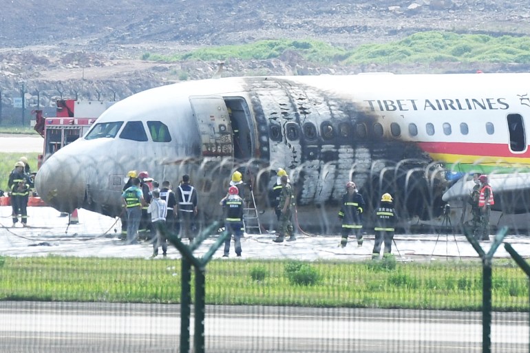 Rescue workers around an Airbus A319 plane of Tibet Airlines caught fire after an aborted takeoff, at Chongqing Jiangbei International Airport