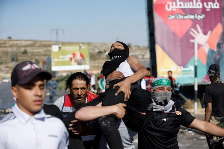 Palestinians carry a demonstrator wounded during clashes with the Israeli forces following a rally marking the 74th anniversary of Nakba. 