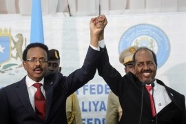 Somalia&#39;s newly elected President Hassan Sheikh Mohamud, right, holds hands with incumbent President Mohamed Abdullahi Mohamed, left after winning the elections in Mogadishu, Somalia, May 16, 2022 [Feisal Omar/ Reuters]