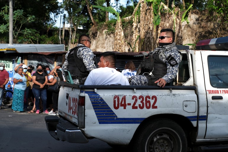 Police officers escort a detained man in El Salvador