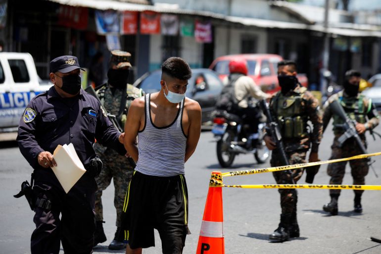 Police officers and soldiers escort a young man to a detention centre in San Salvador