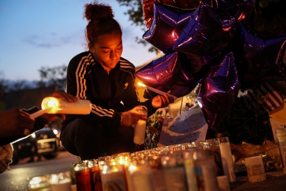 A woman lights a candle at a memorial to Buffalo shooting victims