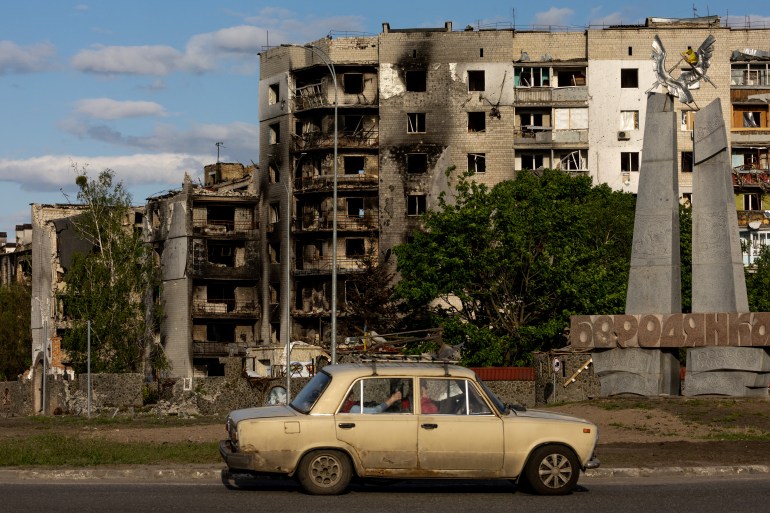 A car drives past in front of destroyed buildings, amid Russia's invasion of Ukraine
