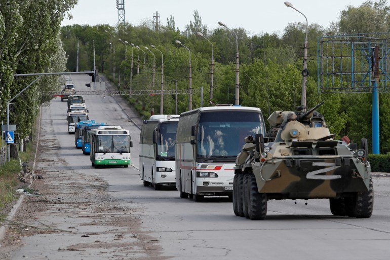 Ônibus que transportam forças ucranianas que se renderam depois de semanas escondidos em Azovstal são escoltados por militares pró-Rússia em 17 de maio de 2022 [Alexander Ermochenko/Reuters]