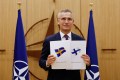 NATO Secretary General Jens Stoltenberg holds up application forms of Sweden and Finland