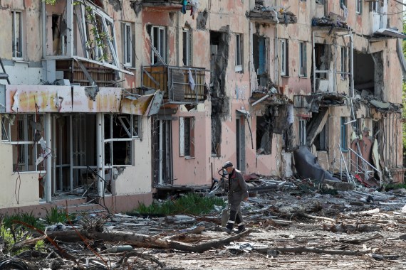 A local resident walks near a building heavily damaged during Ukraine-Russia conflict in the southern port city of Mariupol