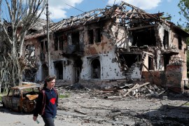 A resident walks past a heavily damaged building in the southern port city of Mariupol [Alexander Ermochenko/Reuters]