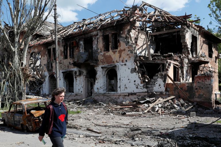 A local resident walks past a heavily damaged building in Mariupol