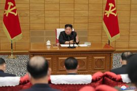 North Korean leader Kim Jong Un speaking at a Workers Party meeting with red flags beside him