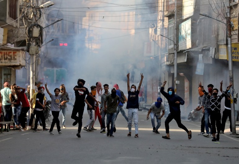 Demonstrators throw stones towards Indian security forces amid tear gas smoke fired by the police during a protest.