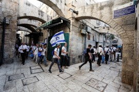 Jewish men carry Israeli national flags as they walk in an alley, inside Jerusalem's Old city