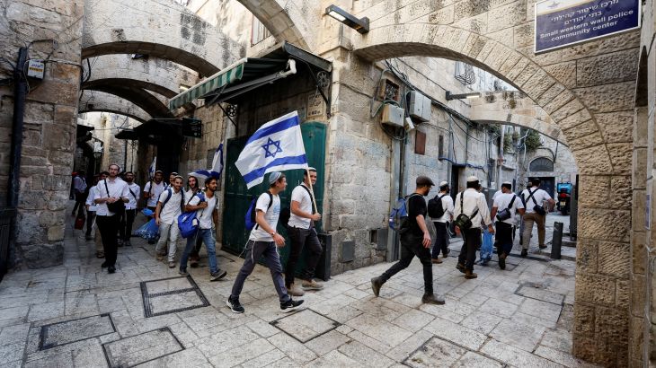 Jewish men carry Israeli national flags as they walk in an alley, inside Jerusalem's Old city