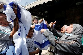 Far-right Israelis wave an Israeli flag in the face of Palestinian women in Jerusalem's Old City