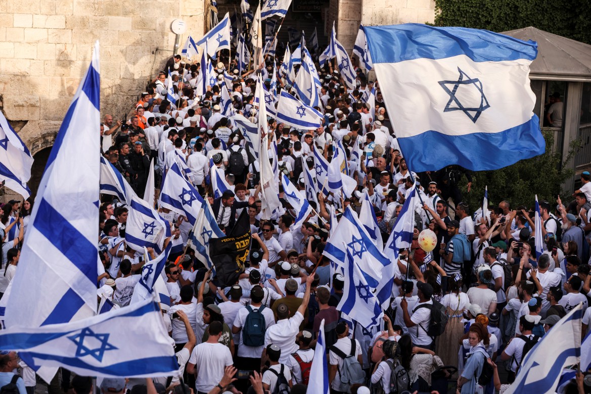 Israelis dance and sing while they hold Israeli national flags by Damascus Gate