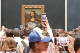 Visitors take pictures and video of the painting "Mona Lisa" after cake was smeared on the protective glass at the Louvre Museum in Paris